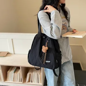 Black casual bucket backpack detail showing large capacity, drawstring closure and cute bear pendant.