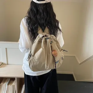 Detailed view of casual khaki nylon drawstring backpack with large capacity and fluffy charm.
