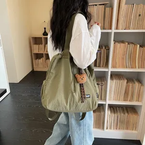 Detailed view of large capacity canvas bucket backpack with cute bear pendant for daily commute.