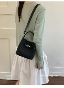 Detailed view of women black bucket shoulder bag with metal lock closure and stylish strap.