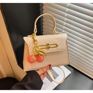Schicke beige Leder Kelly Tasche mit Metallverschluss und süßem Kirschanhänger Damen.