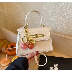 Detailansicht der eleganten beigen Mini-Handtasche mit stilvollem Kirsch-Anhänger und Details.