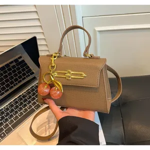 Vintage braune Leder Kelly Tasche mit Metallschloss und Kirschanhänger, elegante Umhängetasche.