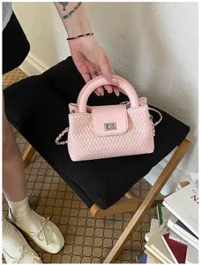 Pink woven leather handbag with metal turn-lock and chain strap, stylish detail view.