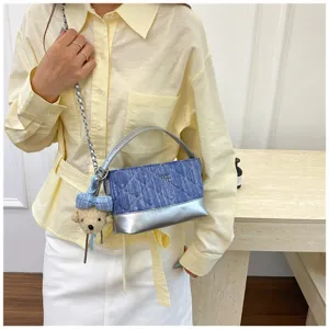 Dettaglio ravvicinato della borsa a tracolla in denim matelassé con catena e ciondolo.