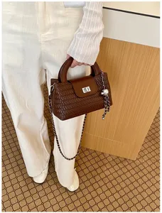 Detailed view of the brown woven leather handbag featuring a metal chain strap and turn lock.