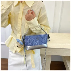 Vista dettagliata della borsa a tracolla trapuntata in denim con fondo argento e ciondolo.