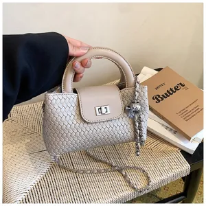 Detailed view of the elegant beige woven leather handbag with a top handle and chic metal chain.