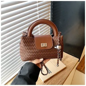 Brown woven top handle crossbody bag with chic chain charm for stylish women daily use.