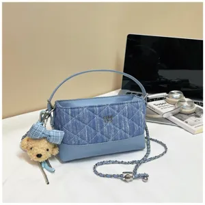 Vista dettagliata della borsa a tracolla in denim trapuntato blu con catena e ciondolo.