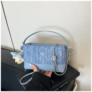 Elegante borsa trapuntata in denim con tracolla a catena, manico e ciondolo orsetto.
