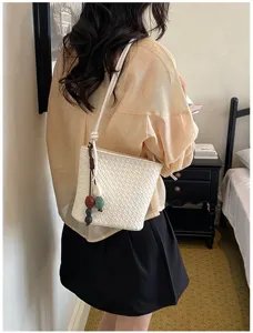 Vue détaillée du sac seau élégant en matière tressée avec pendentif perlé tendance.