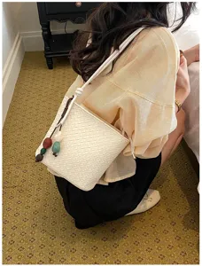 Vue détaillée du sac seau tissé blanc pour femme, sac bandoulière élégant avec perles.