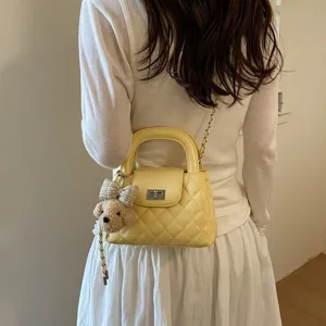Gele gewatteerde bucket bag detail, met schattige pluche berenhanger en kettingriem.
