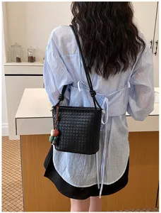 Vue détaillée du sac seau noir tressé avec un motif en cuir élégant et des nœuds de sangle.