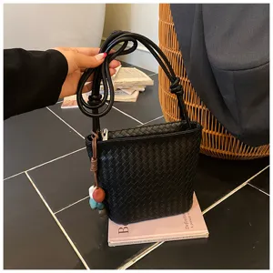 Sac seau tissé noir pour femme, sac bandoulière élégant avec lanière à nœud et charm chic.