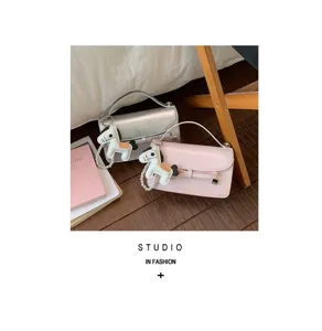 Detalle de bolso cuadrado elegante con bonito colgante de caballo y lazo en rosa y plata.