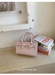Dettaglio borsa a mano in ecopelle rosa con eleganti fiocchi decorativi e manici robusti.