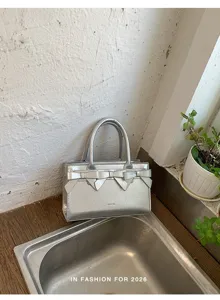 Borsa a mano metallizzata argentata con fiocco chic, dettaglio di tendenza quotidiano.