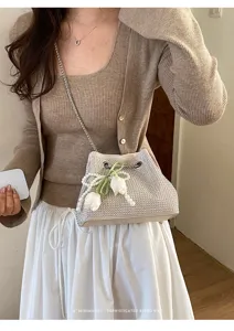 Primer plano de un bolso saco de pedrería con perlas y tulipanes llevado por la modelo.