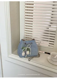 Primer plano del bolso saco de estrás azul con decoración de tulipanes de perlas y cadena.
