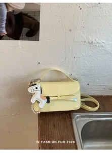 Primer plano del bolso de hombro amarillo con bonito lazo y colgante de caballo.