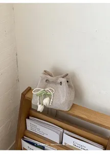 Vista detallada de un bolso cubo de diamantes con abalorio de tulipán de perlas en soporte.