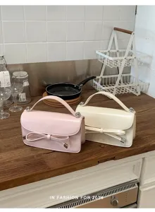 Bolso de mano elegante para mujer con lazo y bandolera de cuero de diseño chic.
