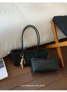 Bolso tote trenzado negro y estuche a juego con colgante en detalle de escena.