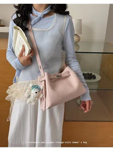 Stylish pink leather bucket bag with shoulder strap and cute bear charm for women.
