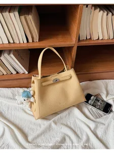 Detailed view of the stylish yellow PU leather handbag with elegant lock and bear charm.