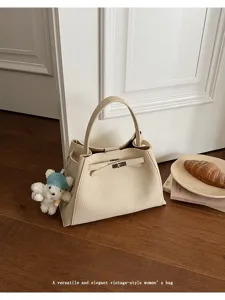 Detailed view of the elegant beige vintage leather handbag with classic lock and cute bear charm.