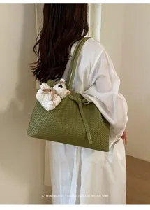 Green woven leather tote bag with stylish shoulder strap and cute bear pendant for women.