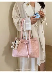 Detailed view of the pink woven tote bag with handle and charm, stylish commuting style.