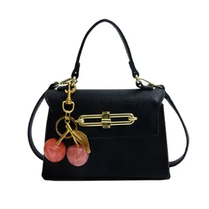 Schicke schwarze Damentasche aus Leder mit goldener Hardware und süßem Kirsch-Anhänger.