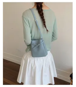 Vue rapprochée et détaillée d'un élégant sac seau en cuir bleu clair avec bandoulière.