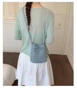 Sac seau en cuir bleu clair détail montrant une boucle élégante et une bandoulière chic.