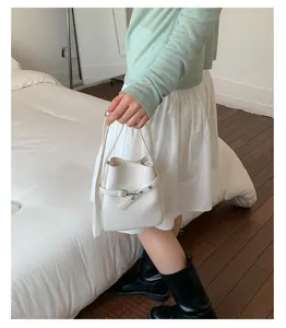 Détail de petit sac seau blanc, sac à bandoulière en cuir tendance pour femme look quotidien.