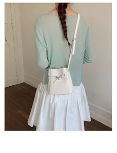 Vue détaillée du sac seau texturé blanc porté en bandoulière, mettant en valeur la belle lanière.