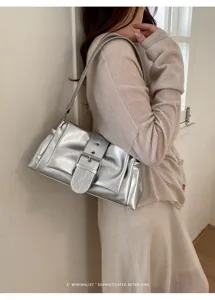 Detailansicht einer trendigen silbernen Schultertasche mit Retro-Schnalle und Knitteroptik.