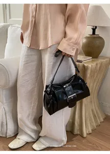 Detailansicht der stilvollen schwarzen Lackleder-Schultertasche mit schickem Metallschnallen-Design.