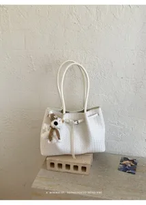 White woven PU leather tote bag detail, featuring double handles and cute bear pendant.