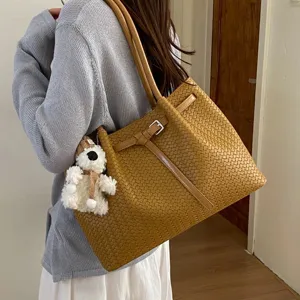 Stylish woven leather shoulder bag with chic buckle strap and cute bear pendant for women.