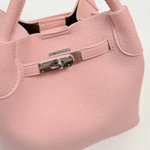 Bolso cubo rosa de piel granulada, vista detallada elegante con cierre metálico.