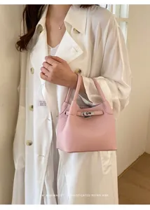 Bolso cubo de cuero rosa con cierre metálico, estilo retro minimalista y elegante.