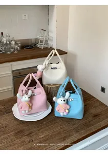 Vista detallada del elegante bolso tipo cubo con patrón de lichi y bonito llavero de peluche.
