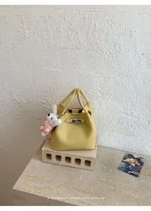 Bolso cubo amarillo minimalista con asa superior y bonito colgante de conejito de peluche.