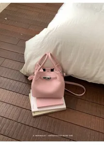 Bolso cubo de piel rosa con asa y cierre de metal. Accesorio elegante para el día a día.