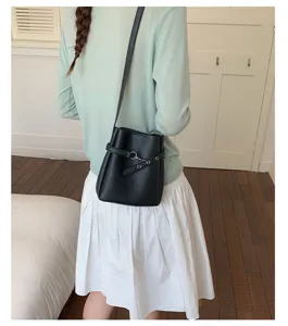 Sac seau noir en cuir PU pour femmes, élégant sac bandoulière tendance avec anneaux métalliques.