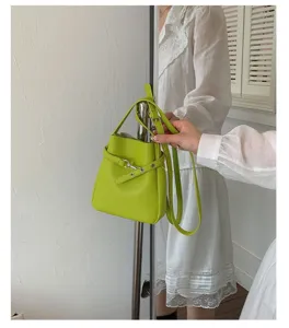Détail de sac seau vert montrant une texture en cuir fin, sangle réglable et quincaillerie.